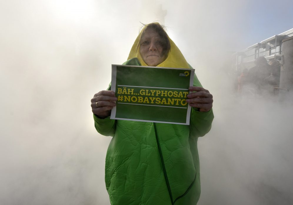 An activists holds a sign 'ugh.. glyphosate #NOBAYSANTO" while protesting against the Bayer Monsanto merger outside the annual shareholders meeting of German chemical giant Bayer AG in Bonn, Germany, Friday, April 28, 2017. The US agrochemical company Monsanto agreed to accept Bayer's offer to purchase the company for US$ 66 billion pending regulatory approval. (AP Photo/Martin Meissner) En demonstrant protesterade 2017 mot att jordbrukskemijätten Bayer köpte upp det lika stora bolaget Monsanto, som bland annat tillverkar bekämpningsmedlet glyfosat