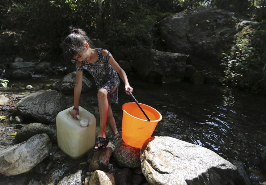 Ett barn hämtar vatten vid en bäck i nationalparken El Ávila som angränsar till Caracas.