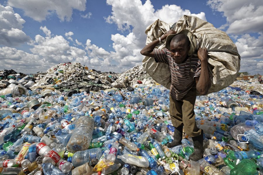 En man samlar plastflaskor i ett sopberg i ett slumområde i Kenyas huvudstad Nairobi.