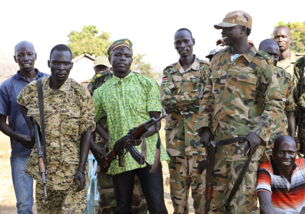 In this photo taken Sunday, Jan. 6, 2019, government and opposition soldiers pose for a picture in the government barracks in Kajo Keji town, where 10 opposition soldiers were staying with the government troops in a makeshift soldier swap, in Kajo Keji county, South Sudan. Since a fragile peace deal was signed in Sept. 2018, South Sudan's previously warring parties have been working to rebuild trust in some of the areas hardest hit by the war. (AP Photo/Sam Mednick) Soldater från regeringsstyrkorna och oppositionella, tillsammans efter fredsavtalet