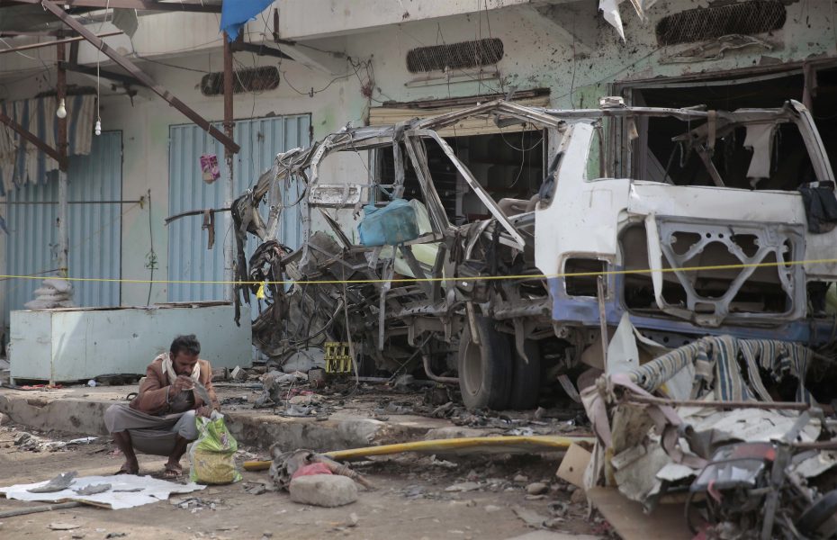 En man går igenom resterna av en sönderbombad buss i Saada, Jemen.