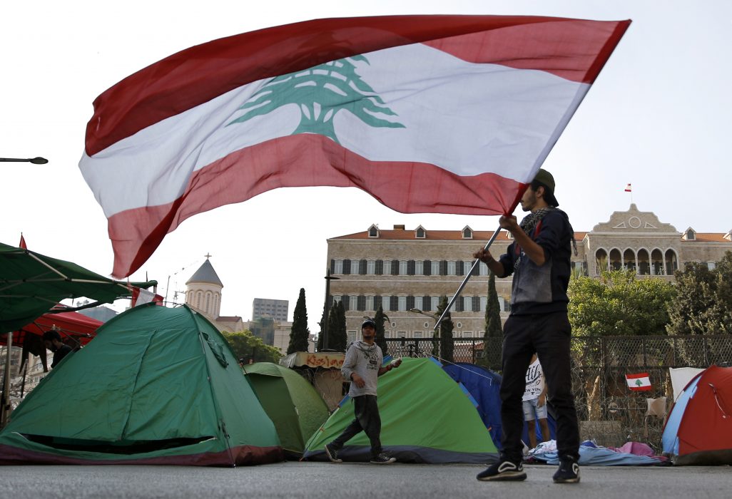 A protester waves the Lebanese flag during ongoing protests against the government, in front of the government palace, in Beirut, Lebanon, Thursday, Oct. 31, 2019. Lebanese security forces were still struggling to open some roads Thursday as protesters continued their civil disobedience campaign. (AP Photo/Bilal Hussein) XBH113 En demonstrant med den libanesiska flaggan under regeringskritiska protester i Libanons huvudstad Beirut den 31 oktober