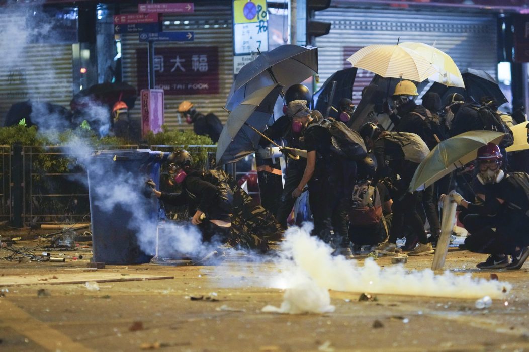 Protesters cover with umbrella as Police fire tear gas in the Kowloon area of Hong Kong, Monday, Nov. 18, 2019. As night fell in Hong Kong, police tightened a siege Monday at a university campus as hundreds of anti-government protesters trapped inside sought to escape. (AP Photo/Vincent Yu) XVT103 Aktivister i Hongkong söker skydd under sina paraplyer mot polisens tårgas vid en protest i mitten av november