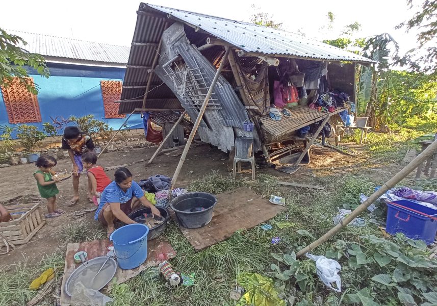En familj utanför sitt hem som skadades under tyfonen förra veckan.