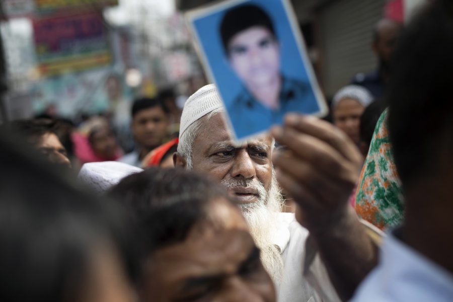 En man håller upp ett porträtt av sin son som dog i en av textilfabrikerna i Rana Plaza i Bangladesh år 2013.