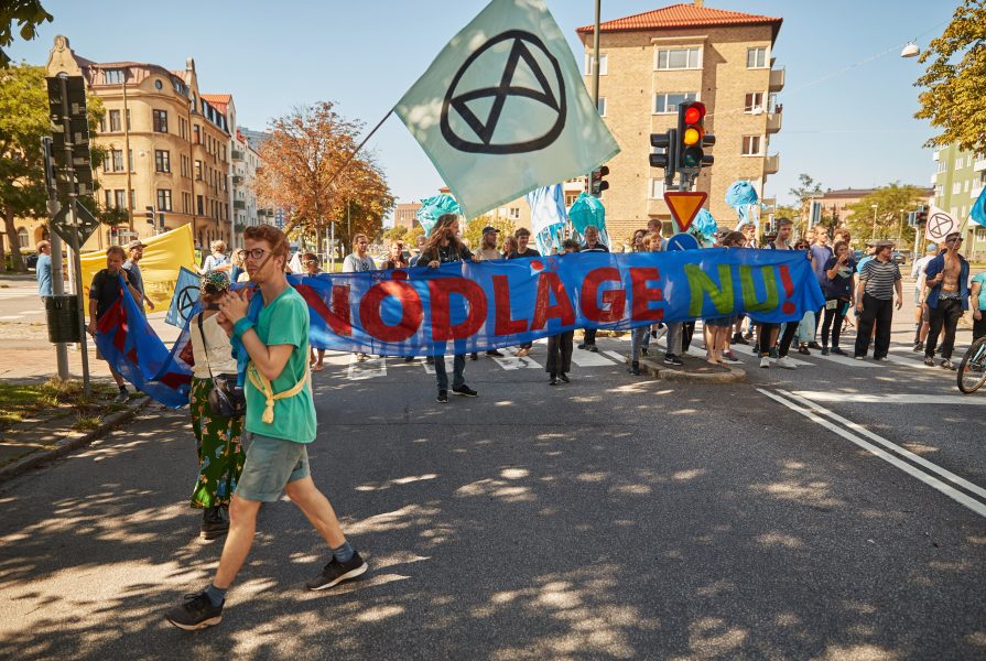 "Klimatnödläge" står det på en banderoll som demonstranter från Extinction Rebellion håller upp när de spärrade av en korsning längs Östra Rönneholmsvägen i Malmö i augusti i år.