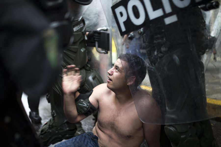 En demonstrant hålls nere av polis under en protest mot regeringen i Colombia.