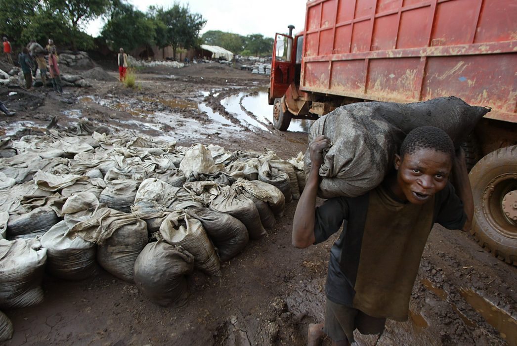 A young man carries wet Cobalt on his back at the Shinkolobwe mine 35kms from the town of Likasi, Democratic Republic of Congo, in this Saturday, April 10, 2004 photo. Massive illicit digging at the uranium mine that fueled the Nagasaki and Hiroshima bombs threatens to put the mine's nuclear ore into terrorist hands, U.N. investigators warned. Cobalt is the main mineral mined in the area. (AP Photo/Schalk van Zuydam) En ung man bär på en säck med blöt kobolt vid en urangruva i Kongo-Kinshasa