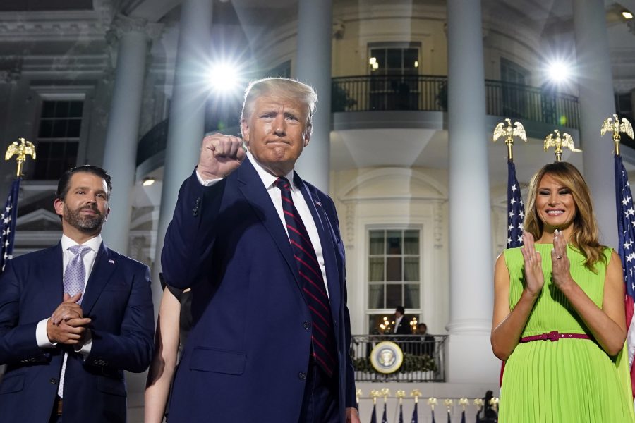 President Donald Trump knyter näven, flankerad av sonen Donald Trump Jr och presidentfrun Melania Trump.