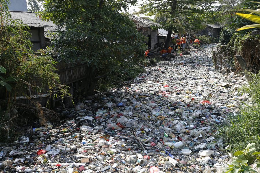 Arbetare samlar skräp ur floden Bajagia i Indonesien.