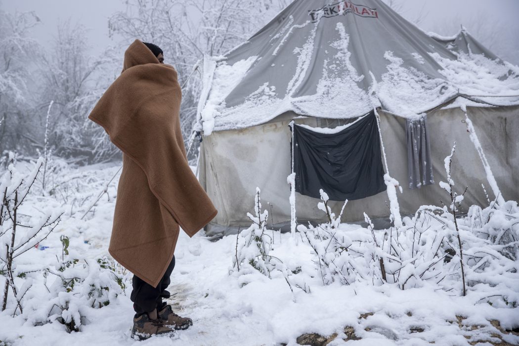 En migrant står intill ett snötäckt tält i ett läger i Vucjak, som låg inte långt ifrån där Lipalägret står, men som stängde ungefär när det öppnade