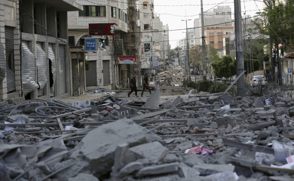 Människor inspekterar resterna av en bombad kommersiell byggnad och en vårdklinik i staden Gaza.