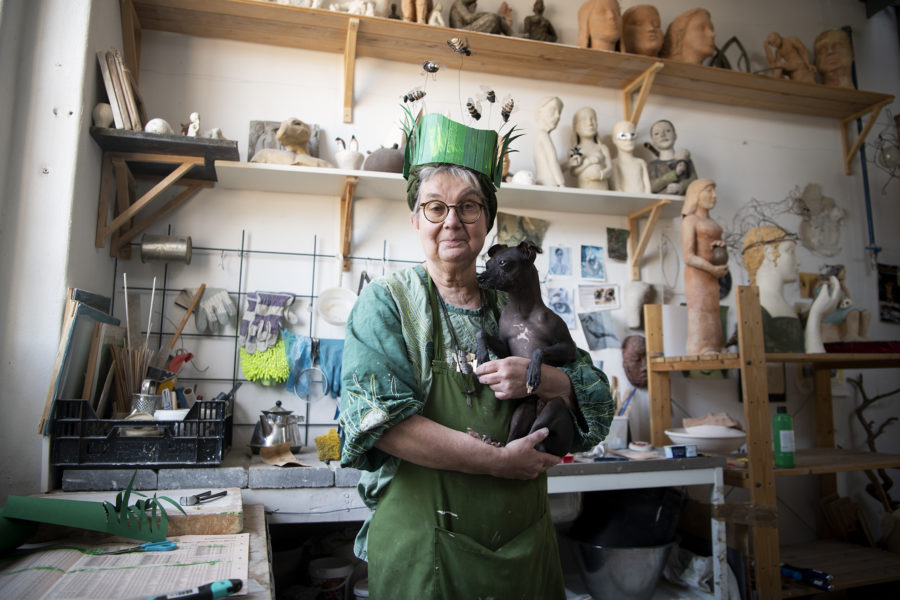Maria Cotellessa i sin ateljé med hunden Killian i famnen och huvudsaken som hon har gjort till biologiska mångfaldens dag.