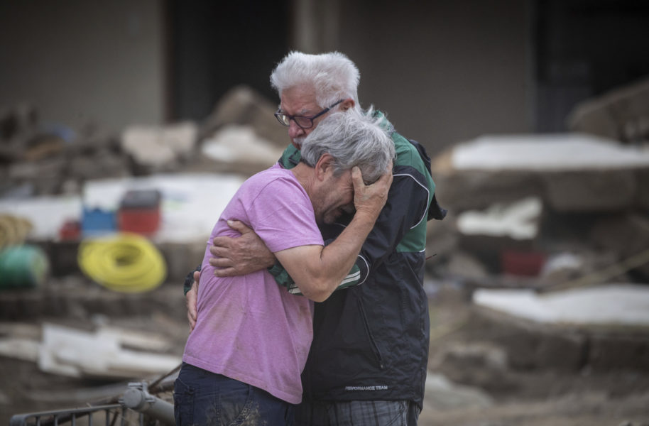 Ett brödrapar gråter i varandras armar framför föräldrahemmet som förstörts i vattenmassorna i tyska Altenahr.
