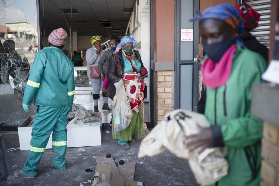 Volontärer röjer upp bråten vid ett köpcentrum som plundrats i sydafrikanska Soweto.