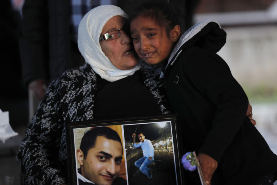 En flicka kramar om sin farmor, som bär på porträtt av en son som omkom i hamnexplosionen i augusti i fjol.