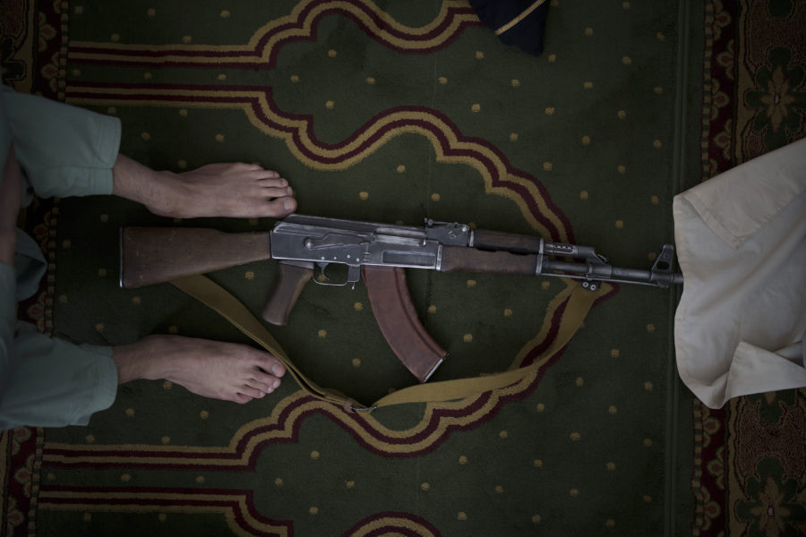 En talibankrigare lägger ifrån sig sitt automatvapen under fredagsbönen i en moské i Kabul.