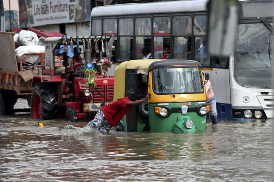 En motordriven riksha knuffas fram genom en översvämmad gata i indiska Bangalore.