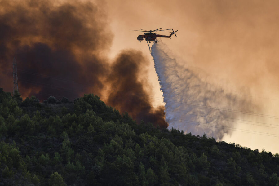 En helikopter deltar i släckningsarbetet vid byn Krestena, 32 mil sydväst om Aten, på söndagen.
