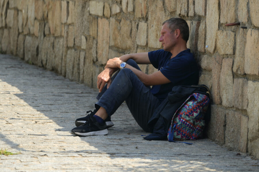 En man vilar i skuggan vid en stenmur i Madrid i juli.