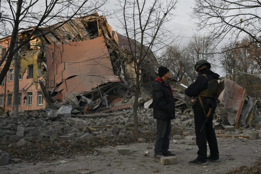 En polis och en man står framför en skola i Kramatorsk som förstörts i en rysk attack.