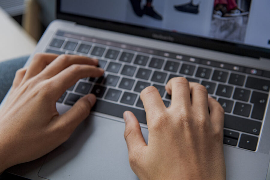 Händer skriver på ett tangentbord till en laptop.