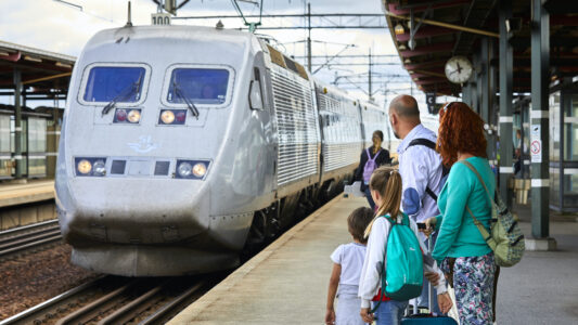 Et tåg och några som står på en perrong.