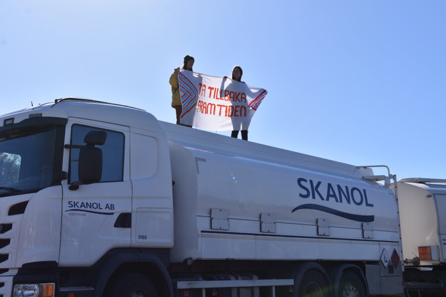 Två personer står på ett lastbilstak med en banderoll med texten &quot;Ta tillbaka framtiden&quot;.