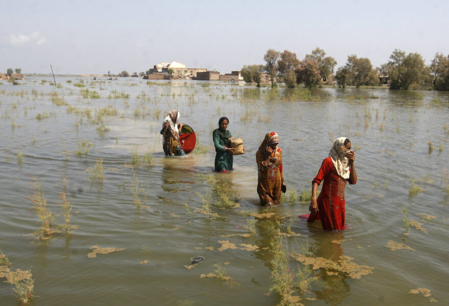 Pakistanska kvinnor vadar genom vattenmassorna i Sindh-provinsen i september 2022.