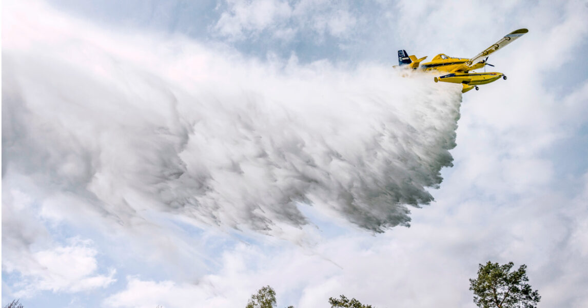 Ett flygplan släpper vatten över en skogsbrand.