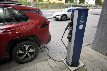 En röd bil laddas vid en laddstolpe.