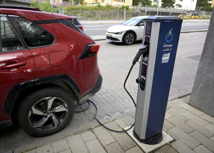 En röd bil laddas vid en laddstolpe.