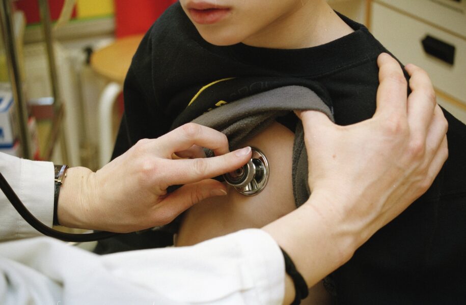 Läkare med stetoskop mot ett barns bröstkorg. Inga ansikten syns.