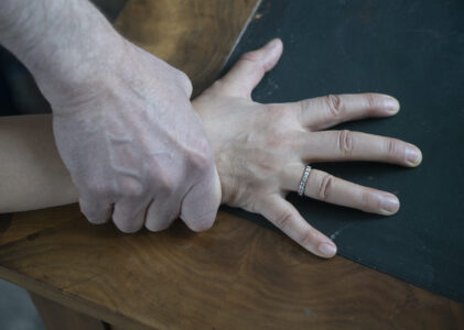 Manshand håller fast kring handleden på kvinnohand.