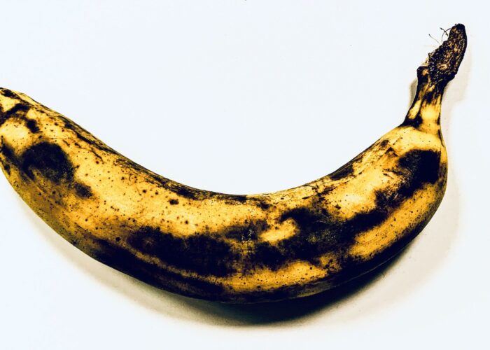 Övermogen svartfläckig banan mot vit bakgrund.