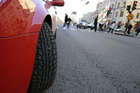 Närbild på dubbdäck på en röd bil, i bakgrunden en stadsgata.