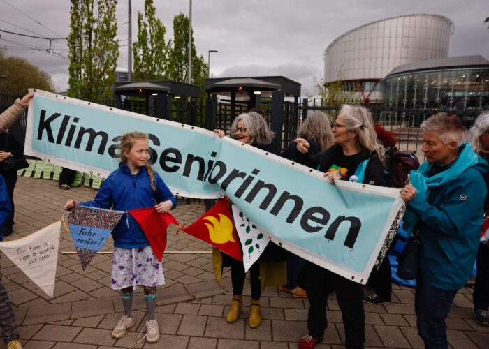 Barn står framför banderoll som hålls av äldre kvinnor.