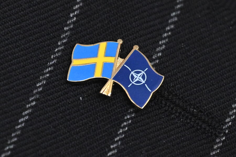 Pin på ett kritstrecksrandigt kavajslag med Natos och Sveriges flagga.