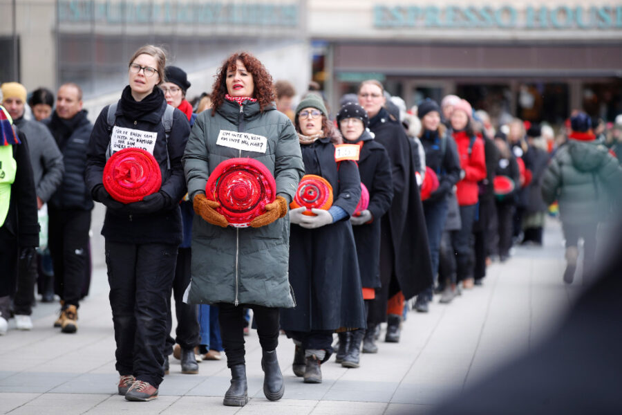 Kvinnor som bär på ihoprullade stickade stycken demonstrerar i Stockholm.