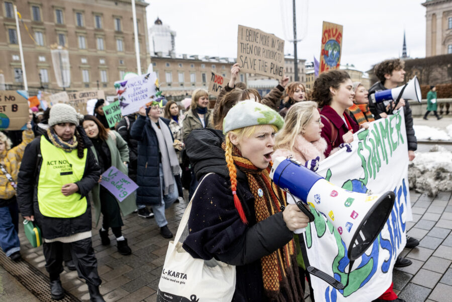 Klimataktivister med plakatet &quot;Nu stämmer vi staten&quot; demonstrerar framför slottet i Stockholm.