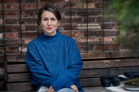 Li Kristjansdottir från Svenska matbanksnätverket i blå tröja framför tegelvägg.