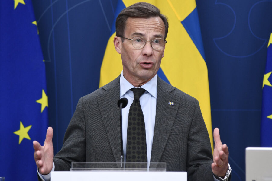 Statsminister Ulf Kristersson framför svenska- och EU-flaggan.