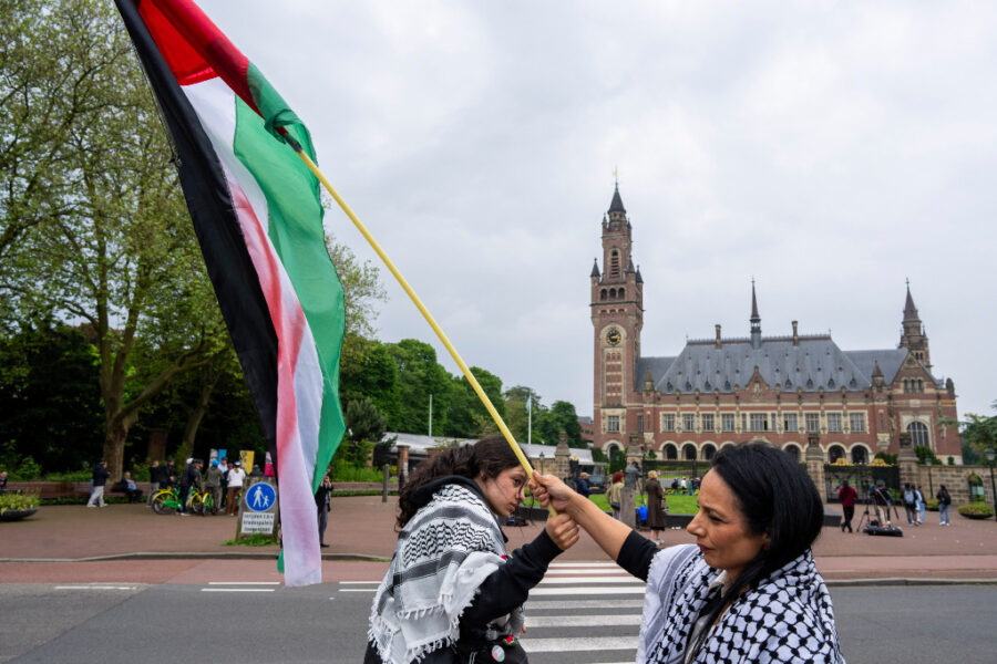 Två demonstranter med Palestinas flagga framför Internationella domstolen i Haag.