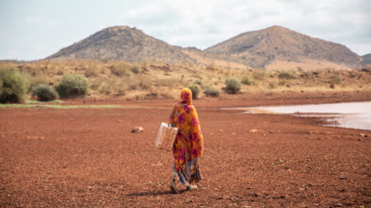 Kvinna går runt i torrt landskap.