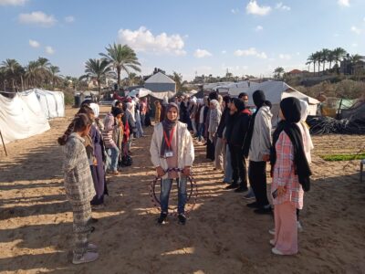 Kvinnor står i två rader i ett tältläger.