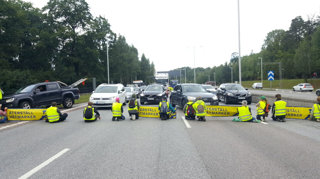 Aktivister blockerar vägbanan på E4 i norra Stockholm i augusti 2022.