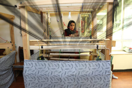 Kvinna vid vävmaskin.