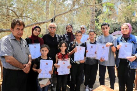 Barn på rad som håller upp diplom.