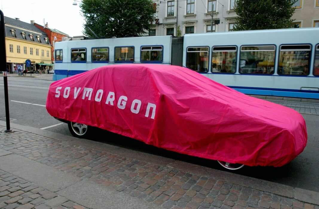 En bil med ett täcke över sig som det står Sovmorgon på.