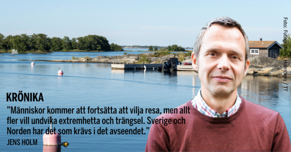 Jens Holm i skjorta och röd tröja med skärgården i bakgrunden.
